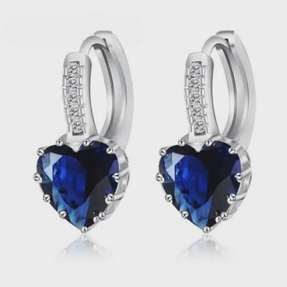 Sterling Silver Crystal Drop Earrings featuring heart-shaped blue gemstones and sparkling accents. Trendy and stylish design.